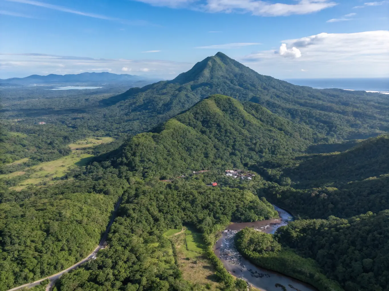 A stunning aerial view of Mount Isarog, showcasing its lush greenery and the surrounding landscape of Camarines Sur. The sky is clear and blue.